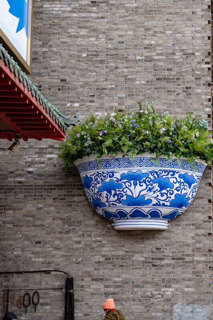 Large Chinese style ceramic planter with lush plants on a brick wall in Harbin, China.
