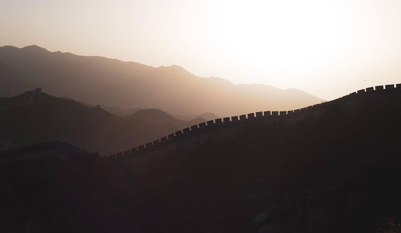 Serene sunset view of the Great Wall of China with misty mountains.