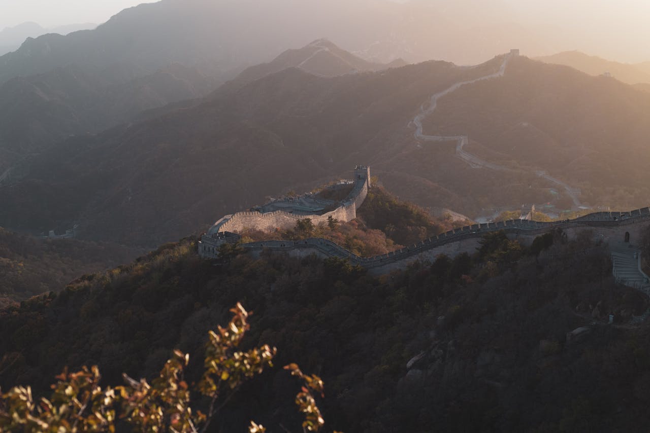 Sweeping view of the Great Wall winding through mountains at sunset, capturing its historic grandeur.